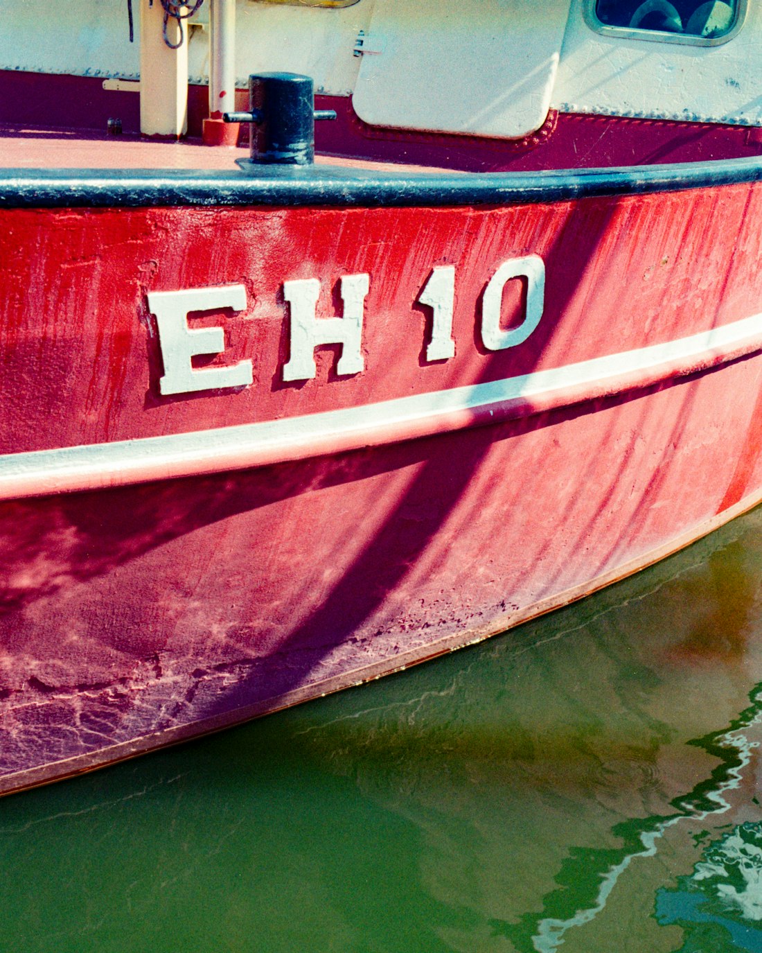 The bow of a red-hulled fishing boat, registration EH 10